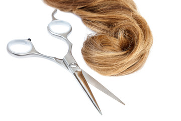 Professional hairdressing scissors and a lock of blond hair.