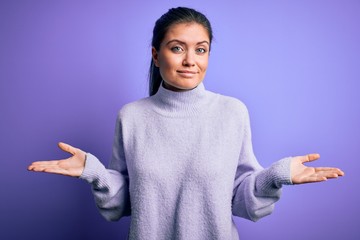 Young beautiful woman with blue eyes wearing casual turtleneck sweater over pink background...