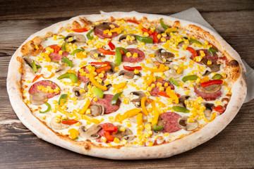 Tasty Italian pizza Mexicano on wooden background. Top view of hot pizza with chili pepper , hot sausages, onion, tomatoes and cheese. Flat lay. Advertising photo for a site or menu.