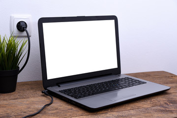 Laptop, computer is charging from a 220-volt outlet on a desk near the wall. Energy, accumulation. Mockup
