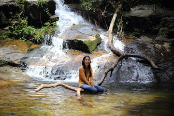 Woman sitting on a branch at Khao Chamao Waterfall, Thailand
