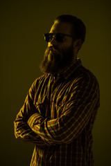 Young bearded man wear in sunglasses with crossed hands isolated on light background.