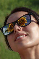 Beautiful girl with sunglasses in a field with sunflowers on a summer sunny day
