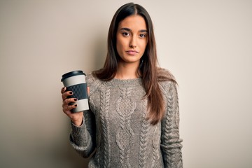 Young beautiful brunette woman drinking glass of coffee over isolated white background with a confident expression on smart face thinking serious