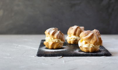 Cream puffs with whipped cream is a classic French dessert also called choux pastry, on black slate...