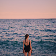 girl in a black swimsuit with her back to the sea