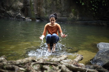 Woman sitting on a rock at a waterfall