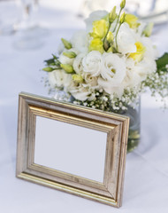 Bridal bouquet standing in a glass near an old, golden photo frame. Copy space.
