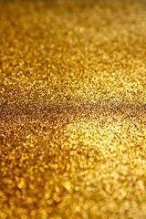 Gold glitter texture sparkling paper background. Abstract twinkled golden glittering background  with bokeh, defocused lights for Christmas holiday, banner, wedding invitation and greeting cards.