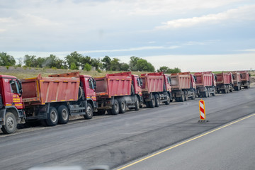 Tipper trucks are standing on the side of the road.
