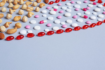 background with colored pills and red capsules with nuts in the corner. Healthy lifestyle concept