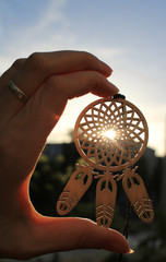 Wooden dream catcher in hand on sunset background.Close-up