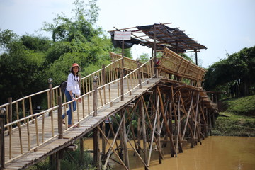 Woman walking across bamboo bridge