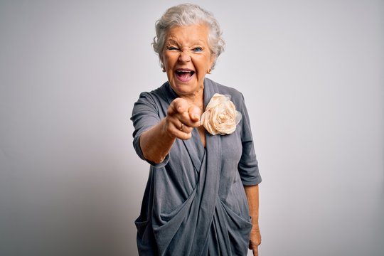 Senior beautiful grey-haired woman wearing casual dress standing over white background pointing displeased and frustrated to the camera, angry and furious with you
