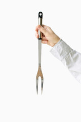 Barbecue fork in female hands on a white background