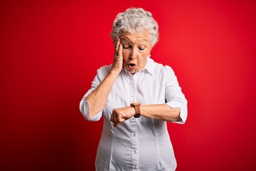 Senior beautiful woman wearing elegant shirt standing over isolated red background Looking at the...