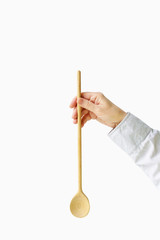 Wooden spoon in female hands on a white background