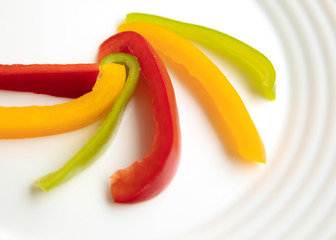 Bulgarian red green yellow pepper slices on white plate