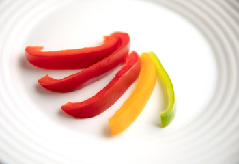 Bulgarian red green yellow pepper slices on white plate