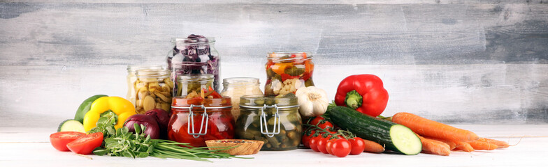 Preserves vegetables in glass jars. Pickled Cucumber, carrot, fermented cabbage and onions on rustic background