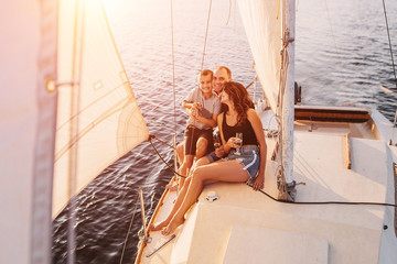 Happy family relaxing on sailboat at sunset