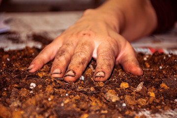 very dirty female hand with soiled nails stays on the ground, closeup.
