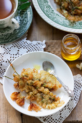 Robinia fritters served with tea and honey on a wooden table. Rustic style.