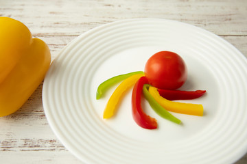 tomato and Bulgarian red green yellow pepper slices on white plate