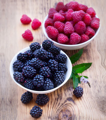 Bowls overflowing with summer berries like raspberries and blackberries.