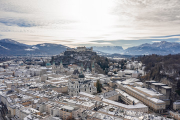 Obraz premium Aerial drone shot view of snowy salzburg city center with view of Cathdrals and fortress in winter