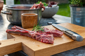 Lamb chops with rosemary and spices and big knife on wooden cutting board