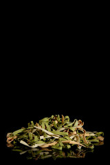Tricolor instant noodles with spinach and tomatoes on a black background.