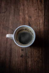 La imagen muestra una taza de café en una mesa de madera