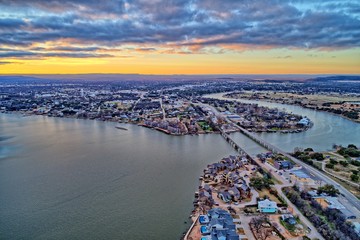 High dynamic range aerial sunset photo of lake, bridge and town under cloudy skies with vivid sunset. Contrasting warm and cool tones.   