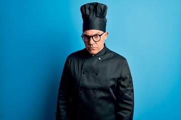 Middle age handsome grey-haired chef man wearing cooker uniform and hat skeptic and nervous, frowning upset because of problem. Negative person.