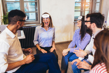 Happy friendly business team having fun at corporate training, funny teambuilding activity,  playing game guess who.