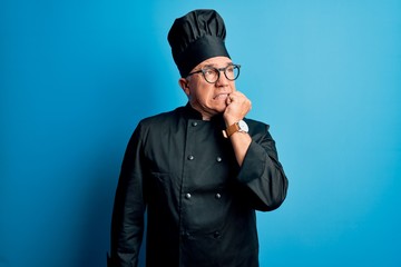 Middle age handsome grey-haired chef man wearing cooker uniform and hat looking stressed and nervous with hands on mouth biting nails. Anxiety problem.