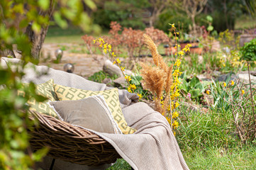 Soft luxury home textile set on whicker chair in beautiful spring garden