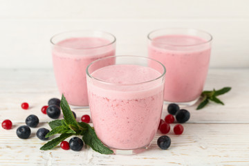 Delicious berry milkshakes on wooden table. Summer drink