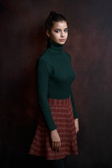 a girl in a green sweater and skirt on a dark background