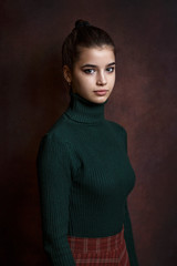 a girl in a green sweater and skirt on a dark background