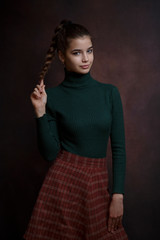 a girl in a green sweater and skirt on a dark background