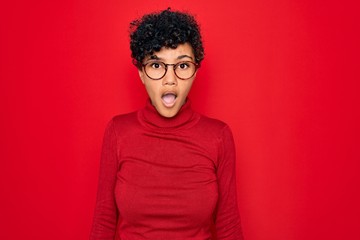 Fototapeta na wymiar Young beautiful african american afro woman wearing turtleneck sweater and glasses afraid and shocked with surprise and amazed expression, fear and excited face.