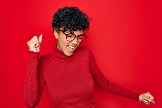 Young beautiful african american afro woman wearing turtleneck sweater and glasses Dancing happy and cheerful, smiling moving casual and confident listening to music
