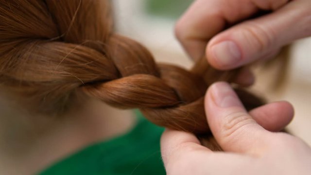 Careful tender, lovely mom braiding daughter’s red hair, preparing for school