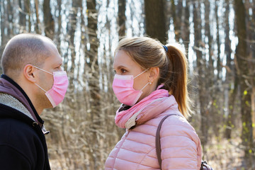 Fototapeta premium Man and woman in medical masks walk in the forest during quarantine.