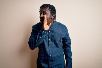 Young handsome african american man wearing casual shirt standing over white background hand on mouth telling secret rumor, whispering malicious talk conversation