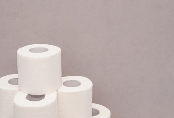 Tower made of white toilet paper rolls against the gray wall in bathroom