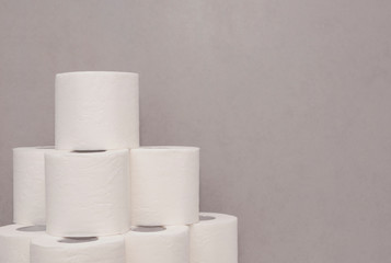 Tower made of white toilet paper rolls against the gray wall in bathroom
