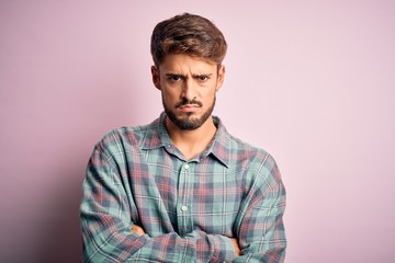 Obraz premium Young handsome man with beard wearing casual shirt standing over pink background skeptic and nervous, disapproving expression on face with crossed arms. Negative person.